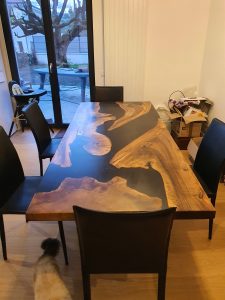 Handcrafted live-edge wooden dining table on display in a showroom, showcasing natural grain and artisan craftsmanship.