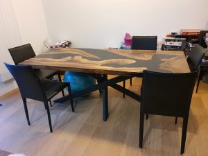 Handcrafted live-edge wooden dining table with dark legs, shown in a showroom for custom wooden tables and doors.