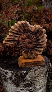 Hand-carved wooden flower sculpture on a wooden pedestal, highlighting artisan woodwork for bespoke tables and doors.