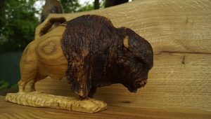 Hand-carved wooden buffalo sculpture displayed on a wooden surface, embodying the craftsmanship behind our wooden tables and doors.