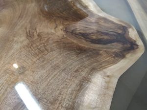 Polished live-edge wooden table slab showing natural grain and edge.