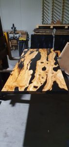 Handcrafted live-edge wooden table in a woodworking shop, showcasing solid-wood tables and doors from a woodworking business.