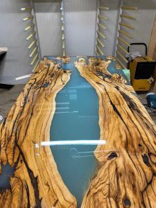 Handcrafted live-edge wooden table with a blue epoxy river, built by a shop specializing in wooden tables and doors.