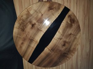 Handcrafted round live-edge wooden table with a black epoxy river running through the center.