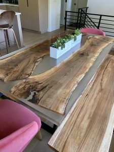 Handcrafted live-edge wooden dining table with a rectangular planter centerpiece in a modern showroom.