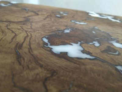 Close-up of a handcrafted wooden table top with rich grain and white resin inlays.