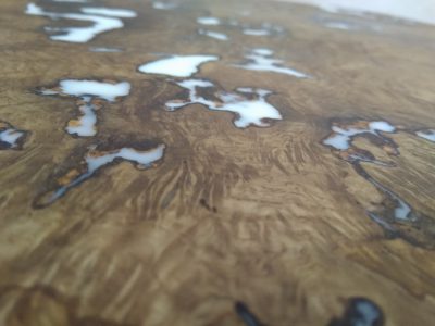 Close-up of a handcrafted wooden table top with rich grain and epoxy resin inlays, showcasing our hardwood tables and doors.