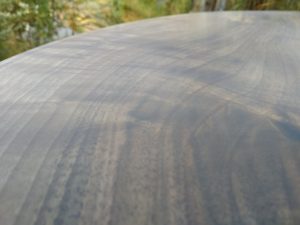 Close-up of a dark, grainy wooden surface, showcasing the craftsmanship behind our wooden tables and doors.