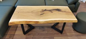 Handcrafted live-edge wooden table with black metal legs in a living room.