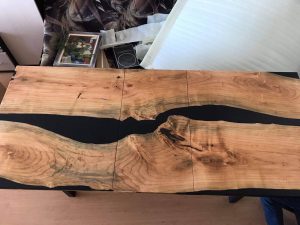 Handcrafted live-edge wooden river table with a black resin seam, showcasing our custom wooden tables.