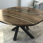 Handcrafted round walnut-finished wooden coffee table with a black metal base.