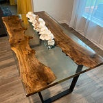 Handcrafted live-edge wooden dining table with black metal legs on display in a showroom.