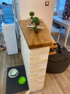 Showroom display of a natural-wood tabletop atop a white brick pedestal, with small plants and decor, highlighting handcrafted wooden tables and doors.