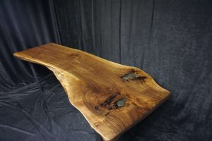 Handcrafted live-edge wooden table top with natural edge, warm grain, and visible knots.