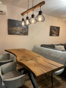 Handcrafted live-edge wooden dining table with industrial pendant lights in a showroom setting.