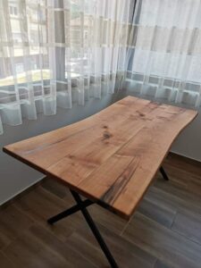 Handcrafted solid wood dining table with natural grain and black metal X-legged base, part of our custom wooden tables and doors collection.