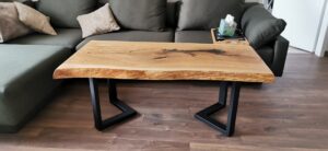 Handcrafted wooden dining table with a natural finish and black metal legs in a modern living room.
