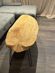 Handcrafted live-edge wooden coffee table with black metal legs in a modern living room.