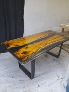 Handcrafted live-edge wooden table with amber resin accents and black metal legs.