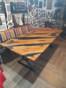 Handcrafted live-edge wooden dining table with black metal legs on display in a showroom, highlighting custom wooden tables and doors.