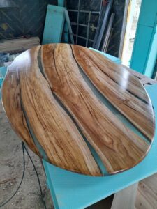Handcrafted round wooden table with natural grain and blue epoxy inlays.