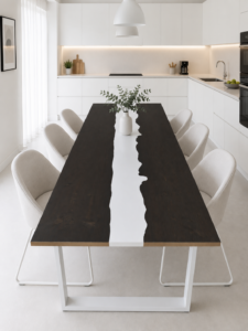 Handcrafted dark wood dining table with a white center inlay in a bright, modern kitchen, surrounded by white upholstered chairs.