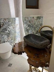 Handcrafted live-edge wooden bathroom vanity with a stone basin, highlighting artisanal wooden tables and doors.