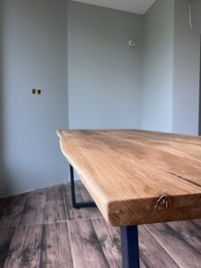 Handcrafted live-edge wooden dining table with black metal legs, from a wood furniture business specializing in tables and doors.