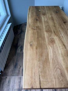 Long natural wood tabletop with visible grain and knots, highlighting craftsmanship for custom tables and doors.