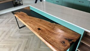 Handcrafted live-edge wooden table top with rich grain, displayed in a workshop as part of our custom tables and doors collection.