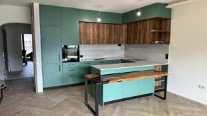 Modern kitchen showroom featuring teal cabinetry, wooden countertops, and a wooden island, showcasing handcrafted wooden tables and doors.