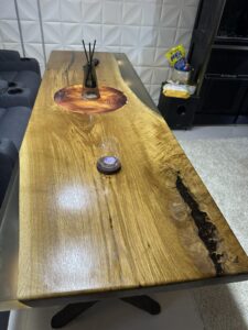 Custom hand-crafted live-edge wooden dining table with natural grain and a resin-filled crack, from a company specializing in wooden tables and doors.