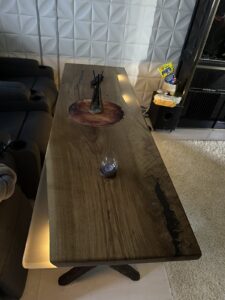 Handmade solid-wood coffee table with a natural edge and warm finish, displayed in a modern living room.