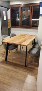 Woodworking showroom showcasing a solid wood dining table with gray upholstered chairs and sample wooden doors on display.