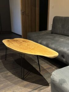 Handcrafted oval wooden coffee table with black metal legs in a living room, part of our custom wooden furniture collection.
