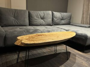 Handcrafted live-edge wooden coffee table with black metal legs in a modern grey living room.