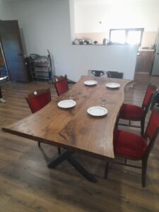 Solid wood dining table with six red-upholstered chairs, showcased in a showroom for custom-made wooden tables and doors.
