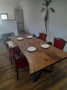 Handcrafted solid-wood dining table with matching chairs in a bright room, highlighting our custom wooden tables and doors.